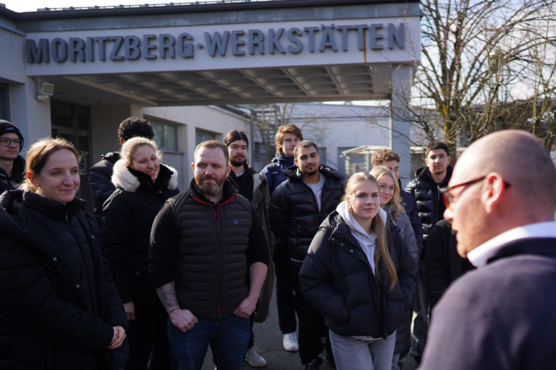 Ein Mitarbeiter der Lebenshilfe im Gespräch mit Auszubindenden von CeramTec