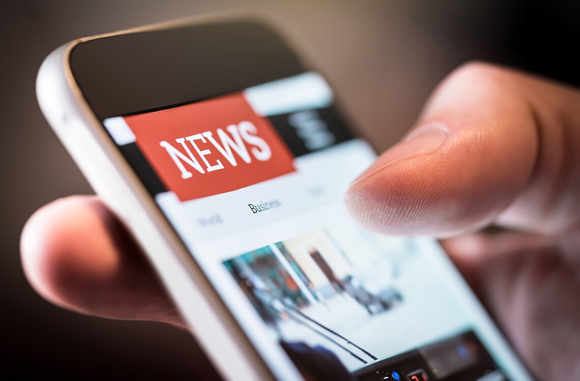 Mann ließt Nachrichten auf seinem Smartphone