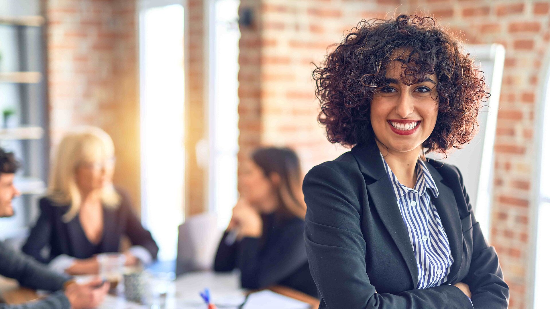A woman with dark curls smiles into the camera