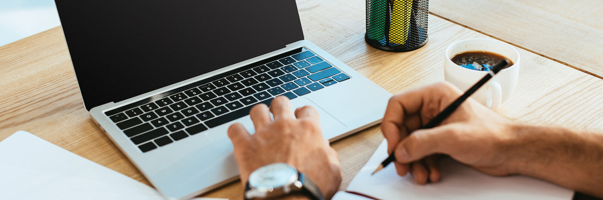 Laptop on the table with person writing
