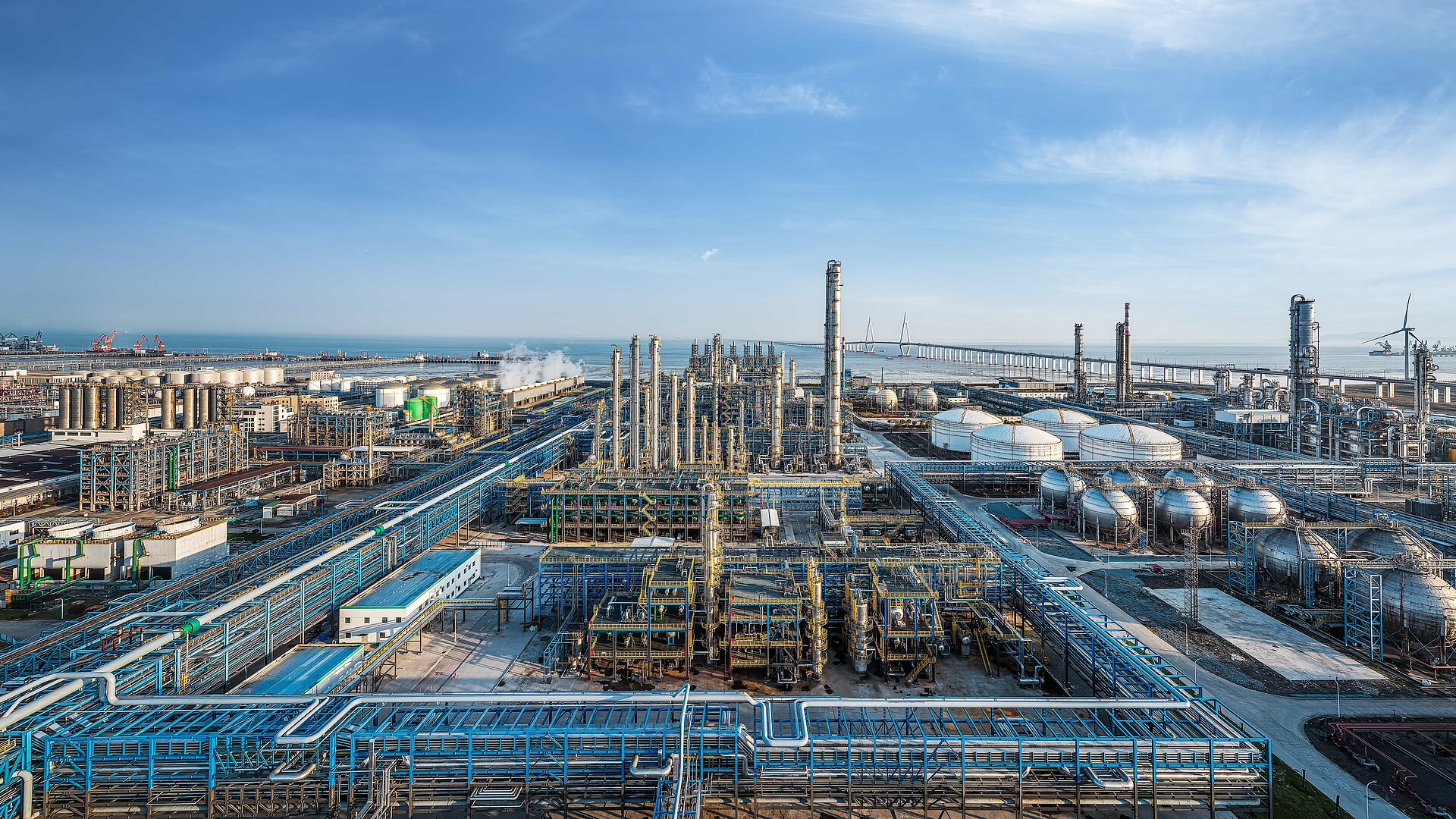 Vue panoramique aérienne d'un immense complexe industriel côtier de raffinage pétrolier et pétrochimique.