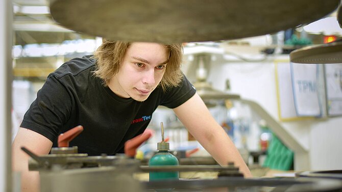 Zaměstnanec společnosti CeramTec se při práci ve výrobě sklání nad strojem