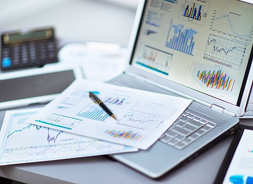 A laptop and papers with financial information on them