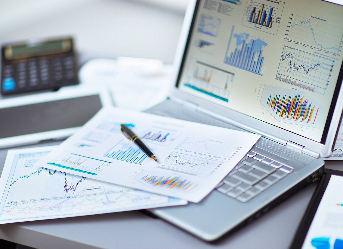 A laptop and papers with financial information on them
