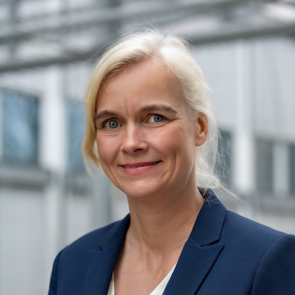 Dr. Carla Kriwet blickt in die Kamera. Im Hintergrund ein Industrieumfeld